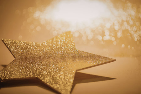 A close-up image of a golden star decoration with a sparkling background, conveying a sense of...