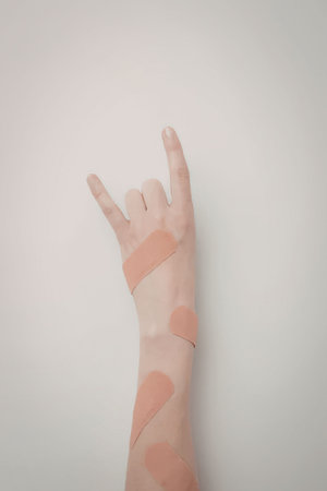 A hand with orange tape applied to the wrist and fingers against a plain white background.