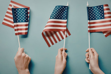 Three hands holding small American flags against a blue background
