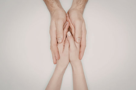 A pair of adult hands gently cradling a child's hands