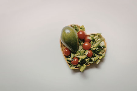 A heart shaped salad with tomatoes on a white background