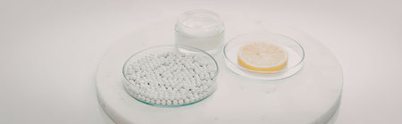 A white table with pills, a bottle, and a lemon slice on a plate.
