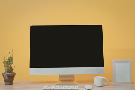 A modern workspace setup with a computer, keyboard, mouse, coffee mug, picture frame, and a small...