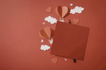 A red background with a red square and hot air balloons, hearts, and clouds.