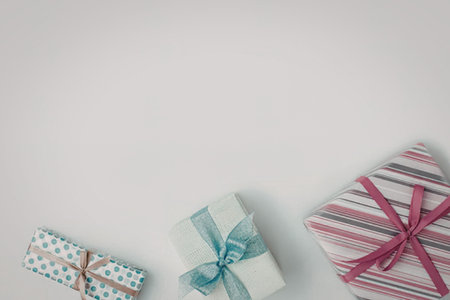Three gifts wrapped in colorful paper with ribbons on a white background