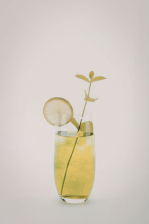 A glass of green cocktail with cucumber slice and mint leaves