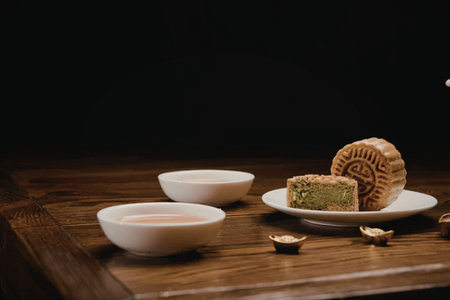 A serene arrangement of traditional Chinese mooncakes and tea on a wooden table, evoking a sense of...