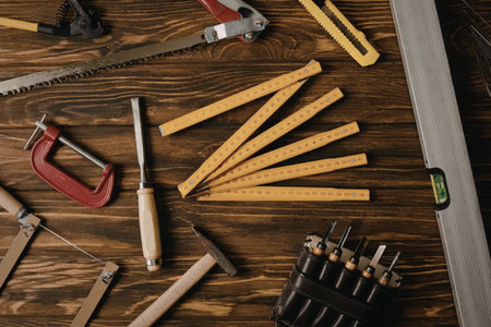 A collection of woodworking tools and orange pencils on a wooden workbench