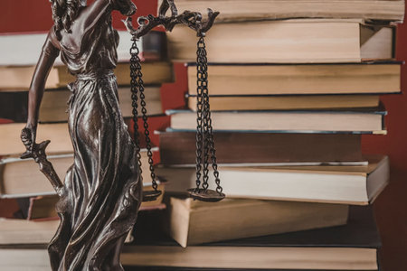 A bronze statue of the goddess of justice standing in front of a stack of books