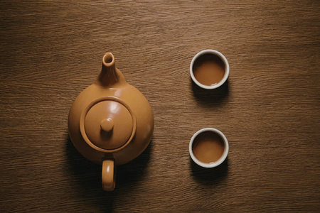 A teapot and two cups of tea on a wooden table