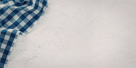 Blue checkered cloth is placed on a white textured surface, providing a simple and rustic background suitable for kitchen or dining table settings and related culinary contexts.の写真素材