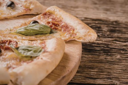 Mini pizza sliced and served on a wooden board with fresh basil leaves and black olives on top, perfect for a quick and delicious meal or snack.の写真素材