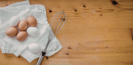 Fresh brown and white eggs are neatly arranged on a white cloth napkin beside a stainless steel...