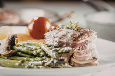Grilled steak served with asparagus and cherry tomatoes on a white plate, showcasing a perfectly cooked meal for a special occasion or romantic dinner.の写真素材
