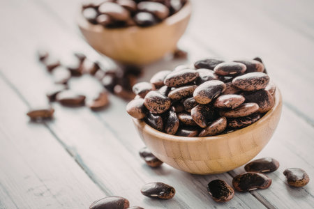 Speckled beans fill wooden bowls on a white wooden table, symbolizing organic food and healthy...