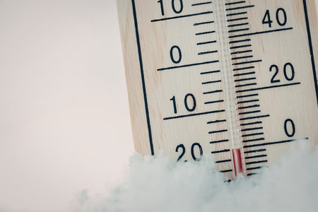 Thermometer partially buried in snow shows a low temperature reading.