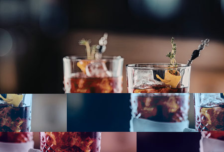Two old fashioned cocktails garnished with orange peel and herb sprigs served in luxurious crystal glassware on a dark wooden table in a sophisticated setting.の写真素材