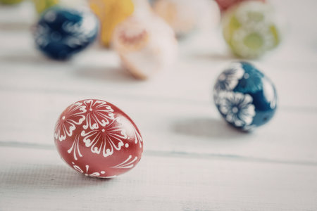 Beautifully decorated red easter egg with intricate white floral pattern surrounded by other...