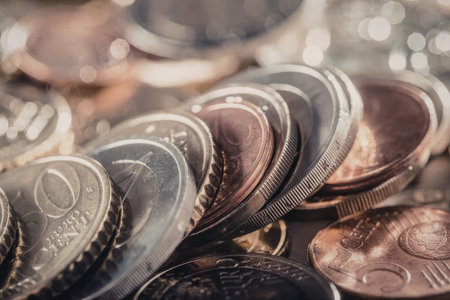 Euro coins are scattered and stacked together showcasing various denominations and shiny metallic...