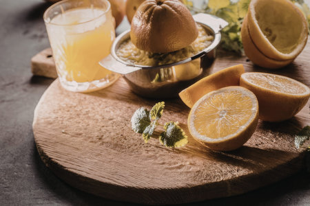 Freshly squeezed orange juice with oranges and mint leaves on a rustic wooden cutting board creating a refreshing and healthy drink atmosphere.の写真素材
