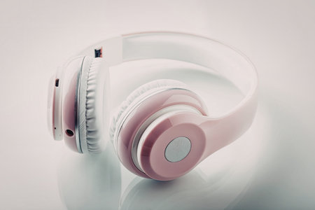 Pink and white headphones rest on a reflective white surface showcasing modern design and style in a...