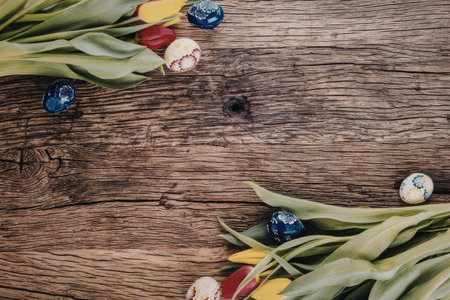 Vibrant tulips and colorful easter eggs beautifully arranged on rustic wooden background creating a...
