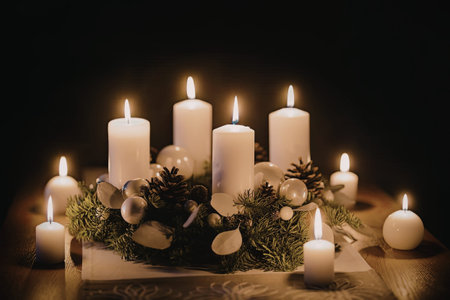 Four white candles in an advent wreath surrounded by festive christmas decorations on a wooden table...