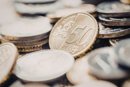 Fifty euro cent coin lies on top of a pile of euro coins with other denominations scattered around.