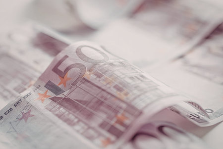 Rolled up 500 euro banknotes displayed prominently with a blurred background showcasing the...