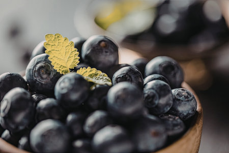 Fresh ripe blueberries fill a wooden bowl, topped with fresh green mint leaves, symbolizing healthy eating and natural ingredients.の写真素材