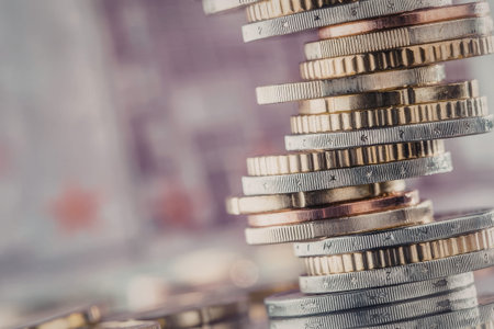 Euro coins stacked precariously on top of each other forming a neat vertical column symbolizing...