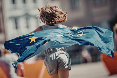 Young girl runs with european union flag flowing behind her symbolizing freedom and unity during an...