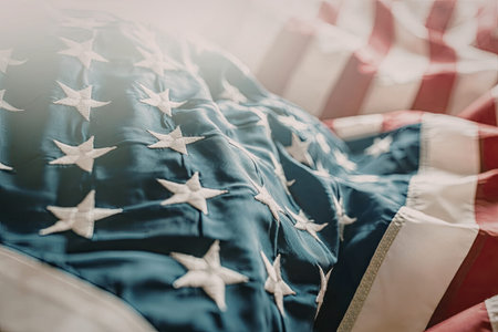 American flag with stars and stripes visible in soft lighting symbolizing freedom and national...