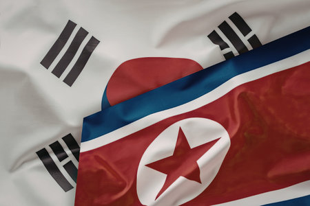Overlapping national flags of North and South Korea represent the historical division, ongoing...