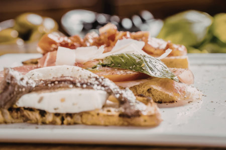 Bruschetta with fresh mozzarella cheese tomatoes and basil on toasted bread topped with parmesan...