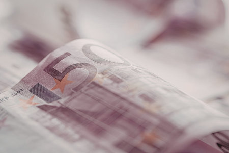 Fifty euro banknote displayed in a close-up view highlighting its purple hue and intricate security...