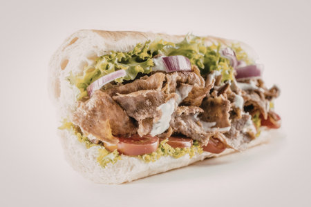 DÃ¶ner kebab sandwich features plentiful seasoned meat fresh lettuce slices juicy tomatoes red...