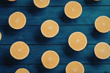 Fresh orange slices are arranged on a blue wooden surface creating a vibrant and healthy snack...