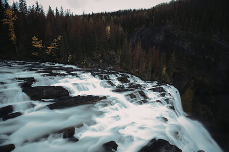 A natural scene of a waterfall flowing over rocks in a forest setting.