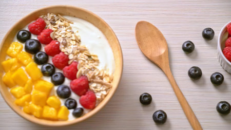 Fresh fruit tart with blueberries, strawberries, peaches, and oats on a gray wooden surface.