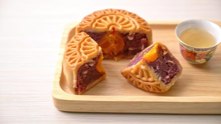 Traditional Chinese mooncakes with intricate designs and sweet fillings, served on a wooden board.
