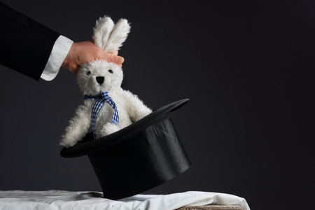 Man in suit pulling a rabbit out of the topper hatの写真素材