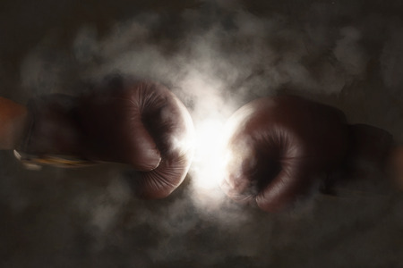 Two brown old boxing gloves hit together