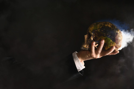 Businessman holding a burning globe While They changed into a skullの写真素材