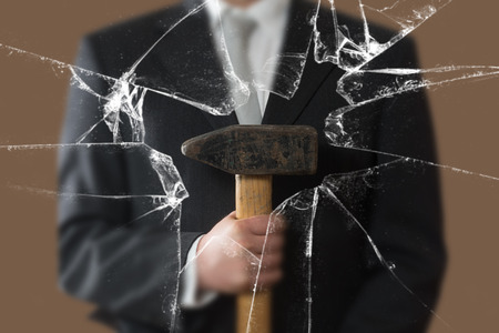 Business Man with Sledgehammer behind a broken Glass Paneの写真素材