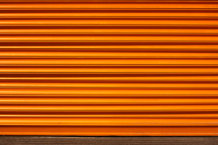 Orange colored shutters that protect warehouses and shops from environmental conditions and ensure their safetyの写真素材