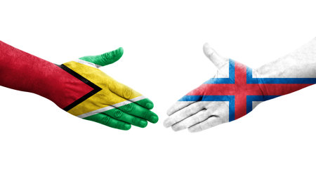 Handshake between Faroe Islands and Guyana flags painted on hands, isolated transparent image.の写真素材