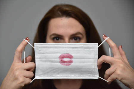 Young girl holding a mask with red lipstick.の写真素材