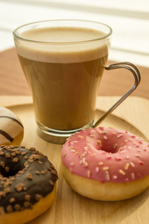 Cup of coffee with donuts on wooden board on window backgroundの写真素材