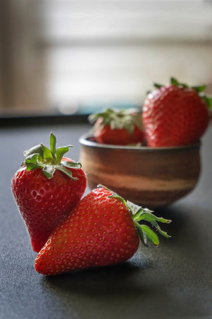 Strawberries in a wooden bowl on a dark background, selective focusの写真素材